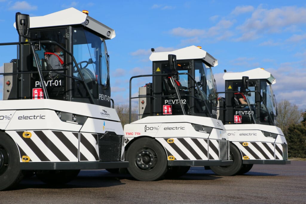 Three white and black electric tow tractors lined up outdoors under a clear blue sky, each marked with "electric" and a unique identification number on their sides.